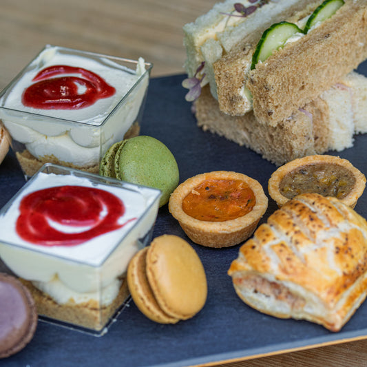 Barnsdale Afternoon Tea from The Helenium Tea Room at Barnsdale Gardens. Assorted finger foods including sandwiches, tarts, and macarons.