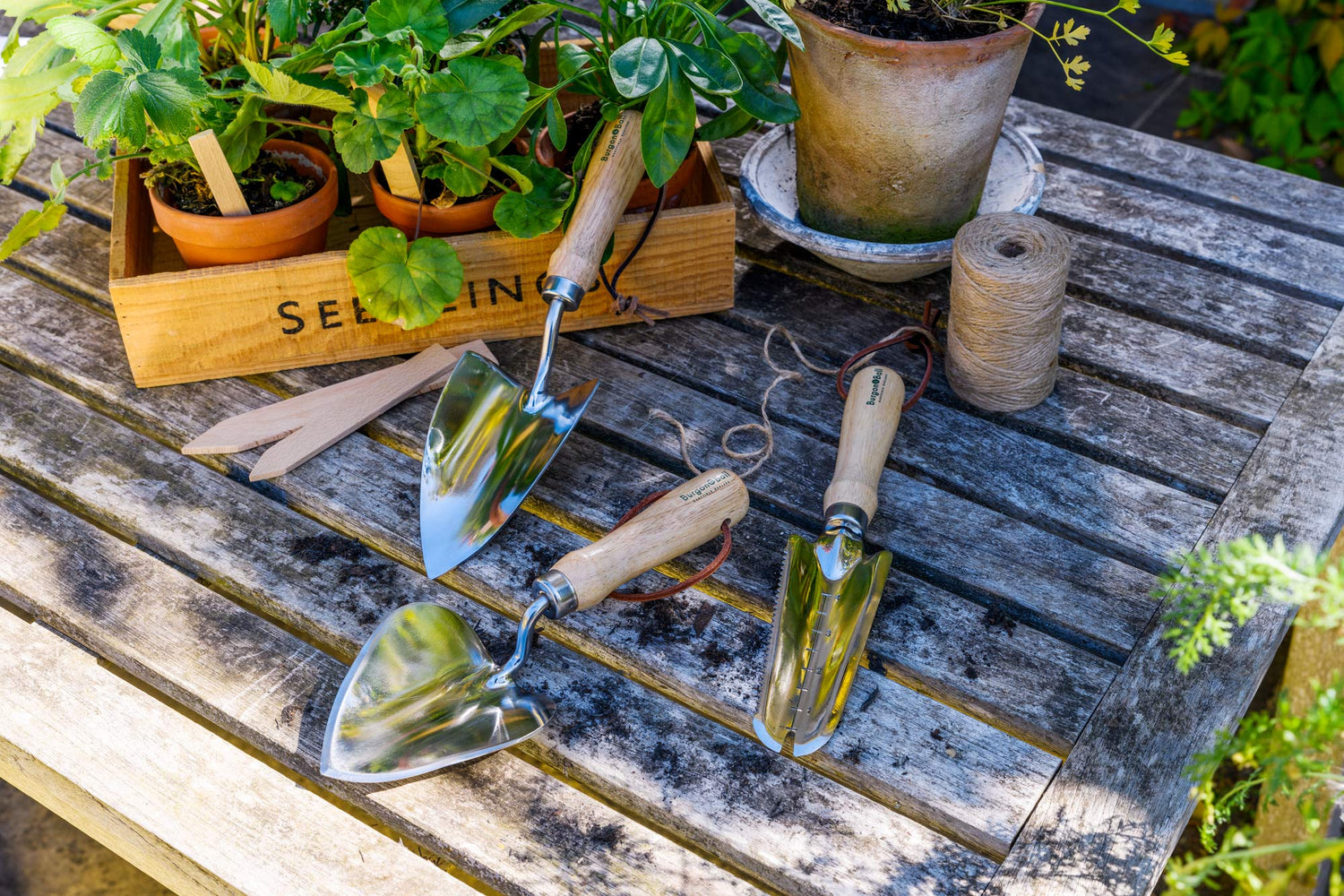 Tools and garden accessories from Barnsdale Gardens header image: hand trowels, wooden labels, string and a box of plants on a wooden table.
