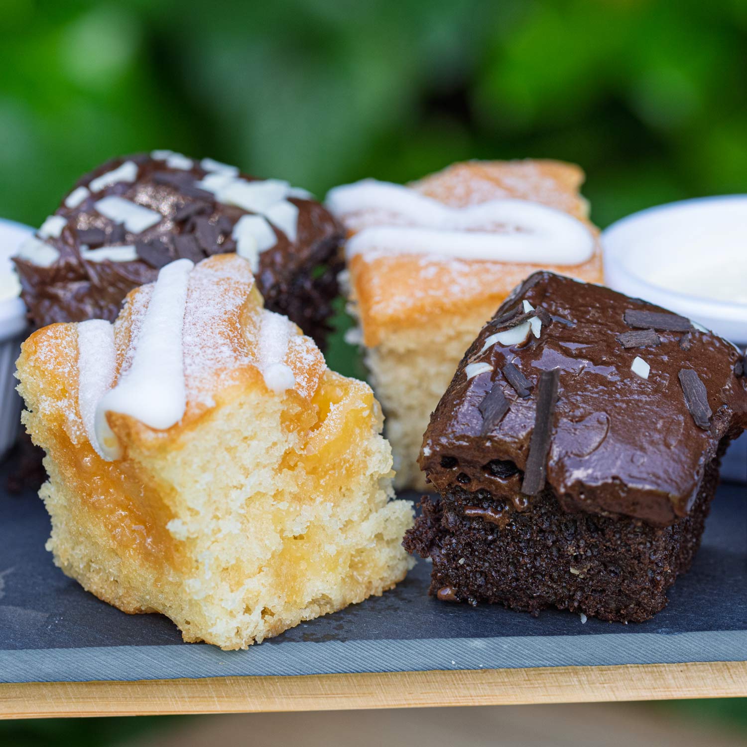 Barnsdale Afternoon Tea from The Helenium Tea Room at Barnsdale Gardens. Assorted small cakes with different toppings on a slate board.