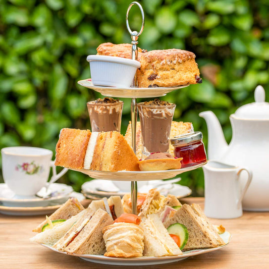 Valentine's Day Afternoon Tea from The Helenium Tea Room at Barnsdale Gardens on bone china cake stand with crockery behind.